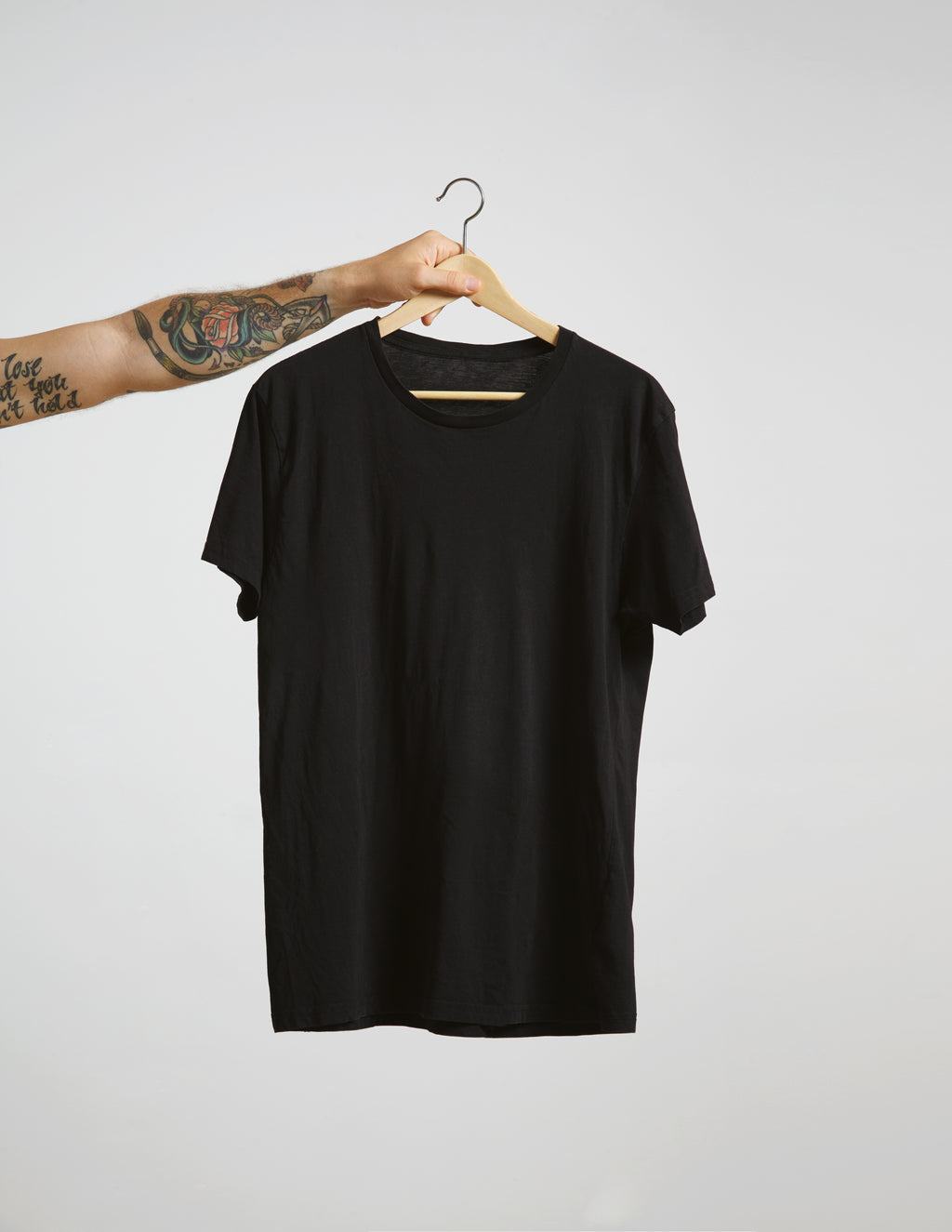 Black t-shirt on a hanger against a plain background