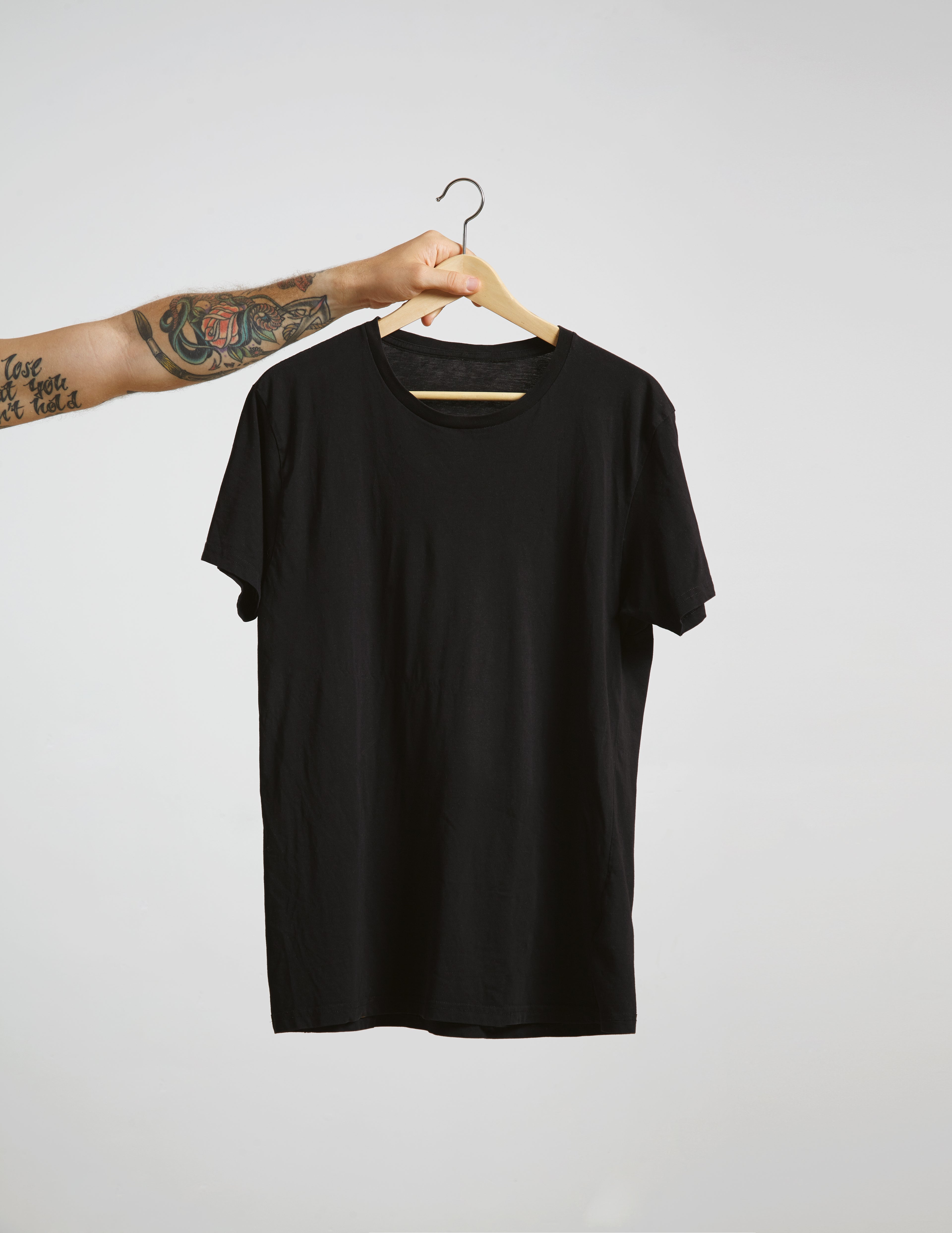 Black t-shirt on a hanger against a plain background